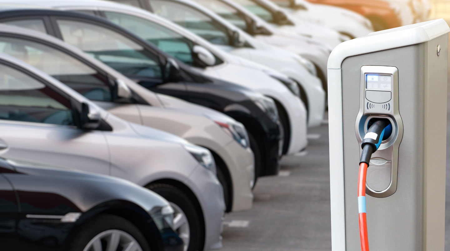 Close-up van een oplaadpoort van een elektrisch voertuig met aangesloten kabel, met zichtbare details van de connector en moderne carrosserie.
